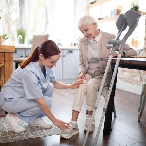 Pflegefachfrau unterstützt ältere Dame mit Krücken